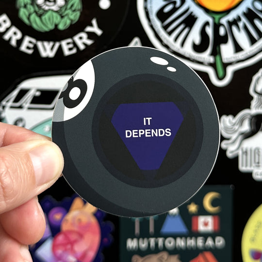 It depends magic 8 ball sticker being held with a sticker door in the background
