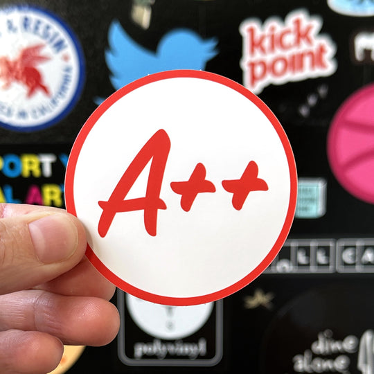 A++ sticker being held with a sticker door in the background