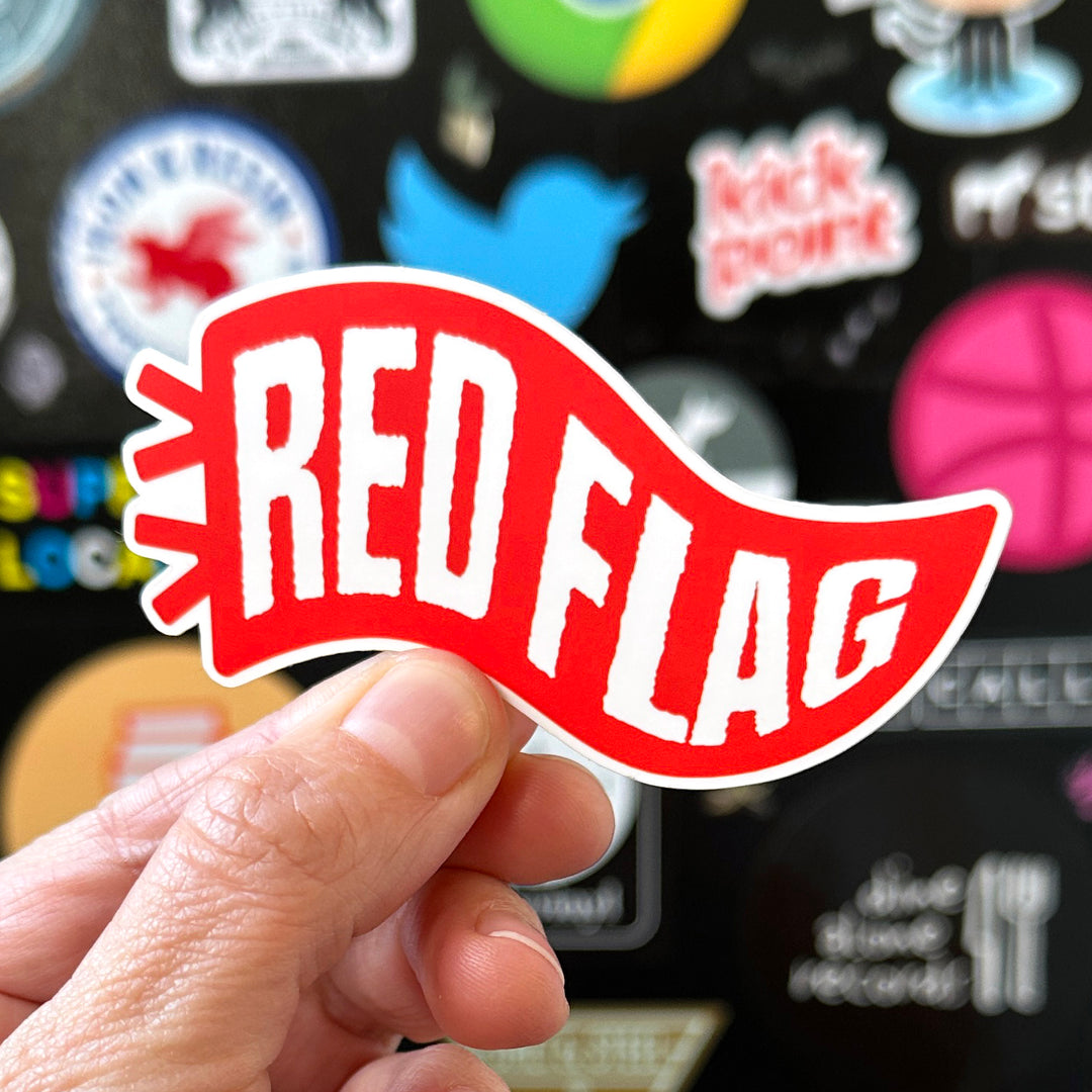 Red flag sticker being held with a sticker door in the background